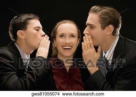 Side profile of two businessmen whispering to a businesswoman View Large Photo Image Picture - Side profile of two businessmen whispering to a businesswoman. Fotosearch
