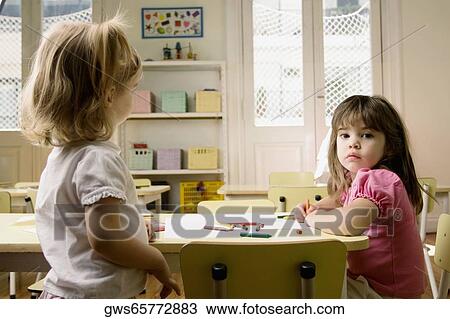 Side profile of two girls in a classroom View Large Photo Image Stock Image - Side profile of two girls in a classroom. Fotosearch