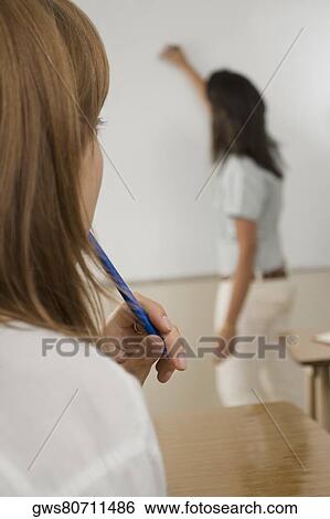 Stock Photograph - Teenage girl with her teacher writing on a white board in the background. Fotosearch