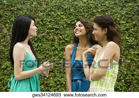 Three young women gossiping View Large Photo Image Stock Image - Three young women gossiping. Fotosearch