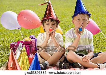 Two boys sitting together and blowing party horns View Large Photo Image Stock Photography - Two boys sitting together and blowing party horns. Fotosearch