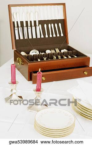 Two burning candles with a cutlery box and stacks of plates on a dining table View Large Photo Image Picture - Two burning candles with a cutlery box and stacks of plates on a dining table. Fotosearch