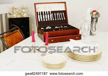 Two burning candles with a cutlery box and stacks of plates on a dining table View Large Photo Image Stock Photo - Two burning candles with a cutlery box and stacks of plates on a dining table. Fotosearch