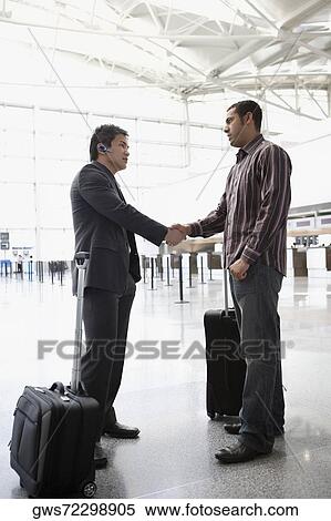 Two businessmen shaking hands at an airport View Large Photo Image Stock Photography - Two businessmen shaking hands at an airport. Fotosearch