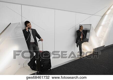 Two businessmen talking on pay phones at an airport View Large Photo Image Stock Image - Two businessmen talking on pay phones at an airport. Fotosearch