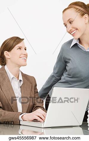 Two businesswomen smiling at each other View Large Photo Image Stock Photo - Two businesswomen smiling at each other. Fotosearch