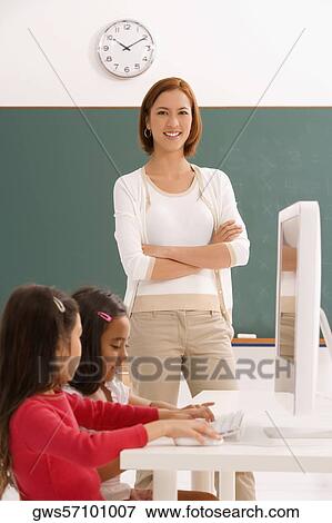 Two girls with their teacher in a classroom View Large Photo Image Stock Photo - Two girls with their teacher in a classroom. Fotosearch