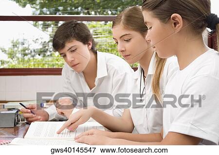 Two schoolgirls and a schoolboy studying together in a classroom View Large Photo Image Stock Photo - Two schoolgirls and a schoolboy studying together in a classroom. Fotosearch