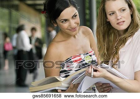Two young women holding books View Large Photo Image Stock Photo - Two young women holding books. Fotosearch