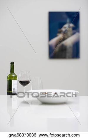 Wine bottle with a glass of red wine and a bowl on a dining table View Large Photo Image Stock Photograph - Wine bottle with a glass of red wine and a bowl on a dining table. Fotosearch