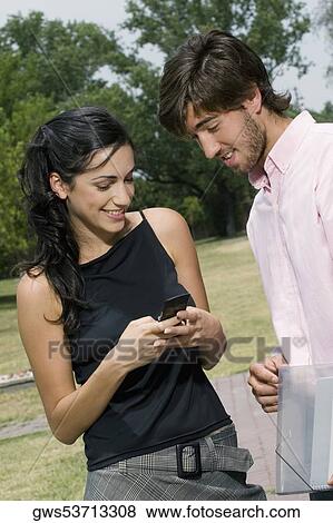 Young couple looking at a mobile phone View Large Photo Image Stock Photo - Young couple looking at a mobile phone. Fotosearch