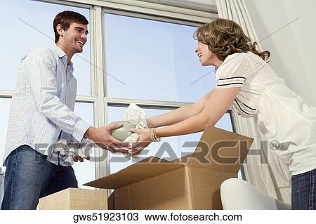 Young couple unpacking a cardboard box and smiling View Large Photo Image Stock Image - Young couple unpacking a cardboard box and smiling. Fotosearch
