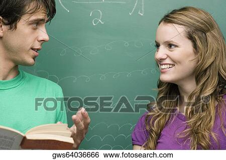 Young man and a young woman talking to each other in a classroom View Large Photo Image Stock Photograph - Young man and a young woman talking to each other in a classroom. Fotosearch