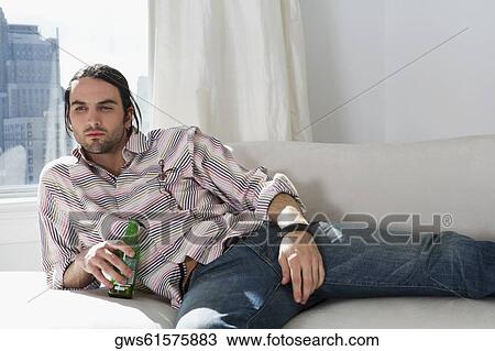 Young man holding a beer bottle View Large Photo Image Stock Image - Young man holding a beer bottle. Fotosearch