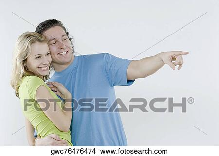 Picture - Young man pointing with a young woman standing beside him. Fotosearch