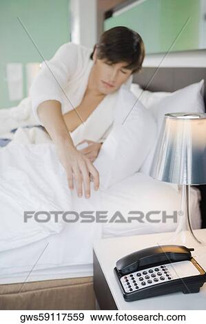 Stock Photo - Young man trying to reach the phone. Fotosearch