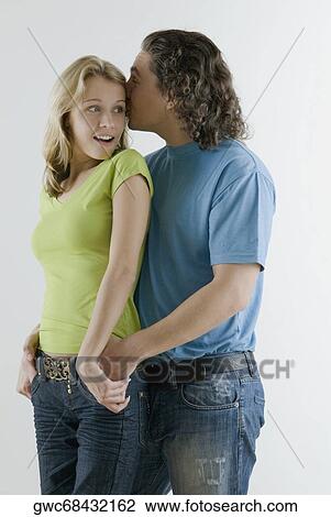 Young man whispering into a young woman's ear View Large Photo Image Stock Image - Young man whispering into a young woman's ear. Fotosearch