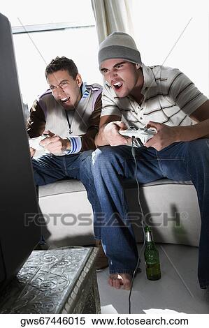 Young men playing a video game View Large Photo Image Stock Photography - Young men playing a video game. Fotosearch