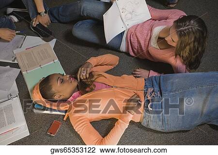 Young woman lying on the floor and another young woman holding a book beside her View Large Photo Image Stock Image - Young woman lying on the floor and another young woman holding a book beside her. Fotosearch
