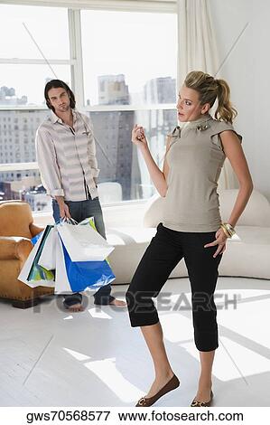 Stock Photo - Young woman standing with a young man holding shopping bags in the background. Fotosearch