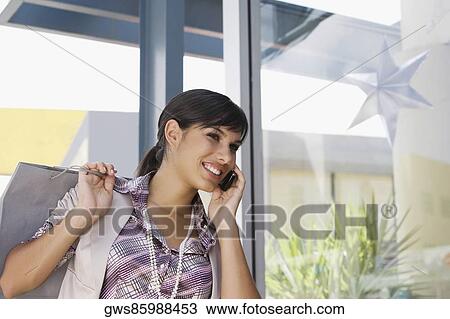 Young woman talking on a mobile phone and smiling View Large Photo Image Stock Image - Young woman talking on a mobile phone and smiling. Fotosearch