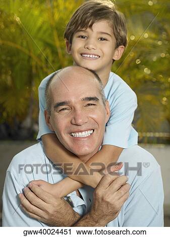 Stock Image - Boy riding piggyback on his father. Fotosearch
