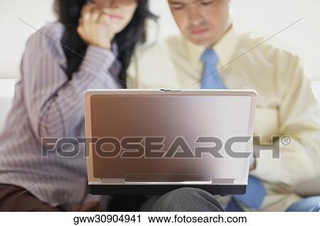 Businessman and a businesswoman sitting in front of a laptop View Large Photo Image Stock Image - Businessman and a businesswoman sitting in front of a laptop. Fotosearch