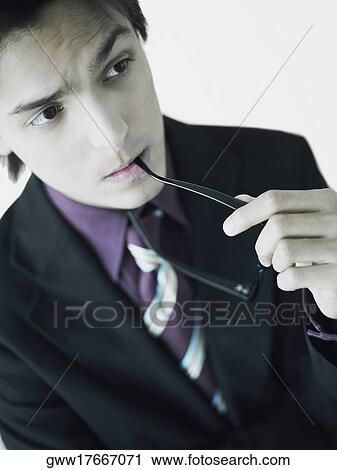Stock Image - Businessman biting his eyeglasses. Fotosearch