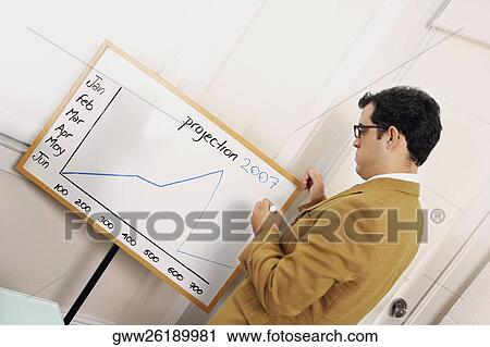 Businessman looking at graph on a flipchart View Large Photo Image Stock Image - Businessman looking at graph on a flipchart. Fotosearch