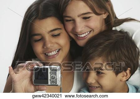 Close-up of a boy and his two sisters taking a photograph of themselves with a digital camera View Large Photo Image Stock Image - Close-up of a boy and his two sisters taking a photograph of themselves with a digital camera. Fotosearch