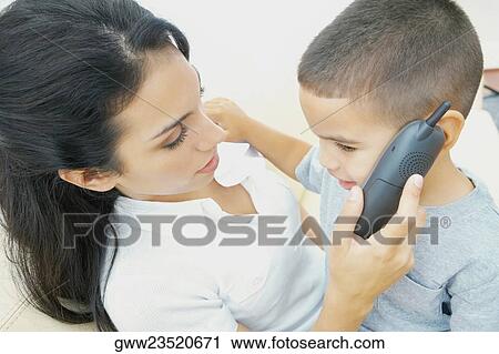 Close-up of a boy sitting on his mother's lap and talking on a mobile phone View Large Photo Image Stock Image - Close-up of a boy sitting on his mother's lap and talking on a mobile phone. Fotosearch