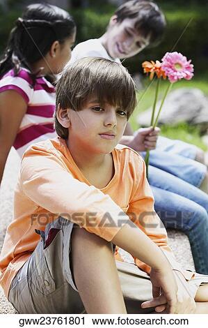 Close-up of a boy thinking with his friends sitting behind him View Large Photo Image Stock Image - Close-up of a boy thinking with his friends sitting behind him. Fotosearch