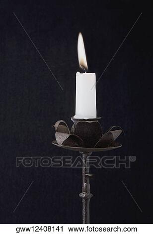 Stock Image - Close-up of a burning candle on a candlestick holder. Fotosearch