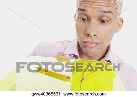 Close-up of a businessman holding a clipboard and making a face View Large Photo Image Stock Image - Close-up of a businessman holding a clipboard and making a face. Fotosearch