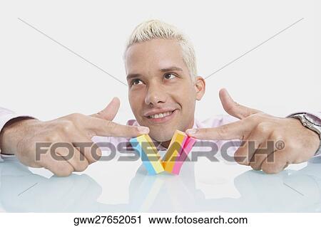 Stock Image - Close-up of a businessman playing with a notepad and smiling. Fotosearch