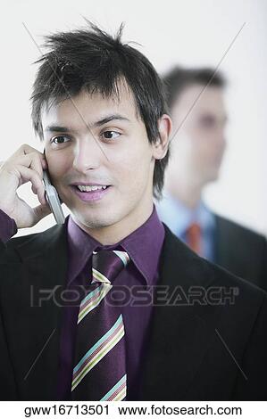Close-up of a businessman using a mobile phone with another businessman behind him View Large Photo Image Stock Image - Close-up of a businessman using a mobile phone with another businessman behind him. Fotosearch