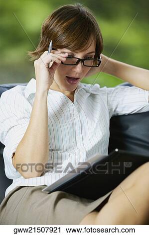 Close-up of a businesswoman adjusting her eyeglasses and reading a file View Large Photo Image Stock Image - Close-up of a businesswoman adjusting her eyeglasses and reading a file. Fotosearch