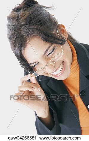 Stock Image - Close-up of a businesswoman adjusting her eyeglasses and smiling. Fotosearch