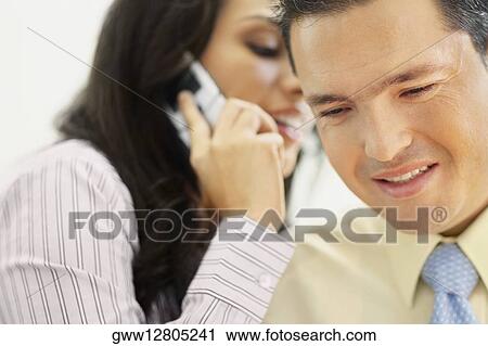Close-up of a businesswoman talking on a flip phone and whispering to a businessman View Large Photo Image Stock Image - Close-up of a businesswoman talking on a flip phone and whispering to a businessman. Fotosearch