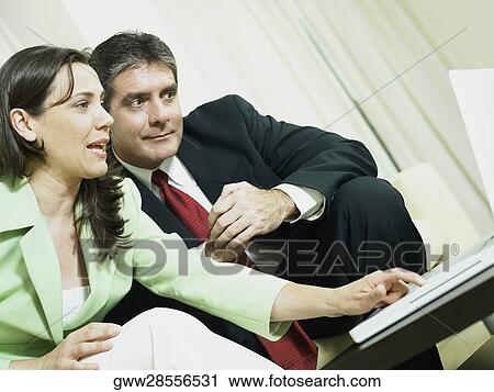 Close-up of a businesswoman working on a laptop and a businessman sitting beside her View Large Photo Image Stock Image - Close-up of a businesswoman working on a laptop and a businessman sitting beside her. Fotosearch