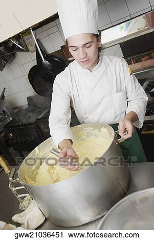 Stock Image - Close-up of a chef preparing food in a commercial kitchen. Fotosearch