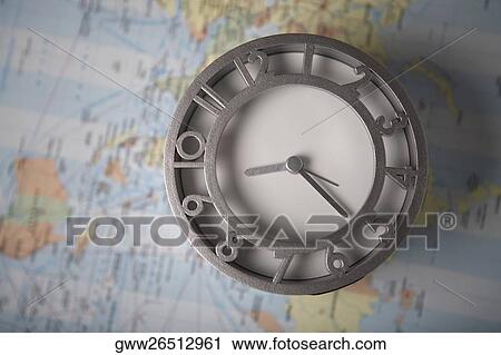 Stock Image - Close-up of a clock in front of a map. Fotosearch
