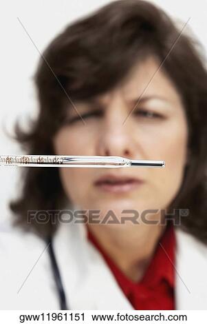 Stock Image - Close-up of a female doctor looking at a thermometer. Fotosearch