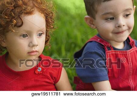 Close-up of a girl and her brother sitting on the grass View Large Photo Image Stock Image - Close-up of a girl and her brother sitting on the grass. Fotosearch