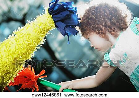 Stock Image - Close-up of a girl hitting a pinata with a stick. Fotosearch