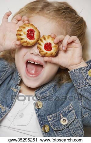 Close-up of a girl holding two biscuits on her eyes View Large Photo Image Stock Image - Close-up of a girl holding two biscuits on her eyes. Fotosearch