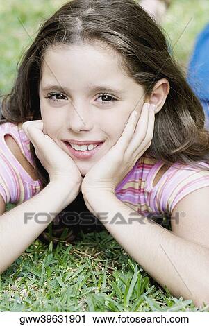Close-up of a girl lying on the grass and smiling View Large Photo Image Stock Image - Close-up of a girl lying on the grass and smiling. Fotosearch