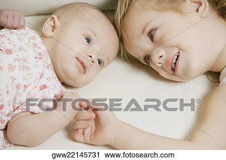 Close-up of a girl smiling with her sister View Large Photo Image Stock Image - Close-up of a girl smiling with her sister. Fotosearch