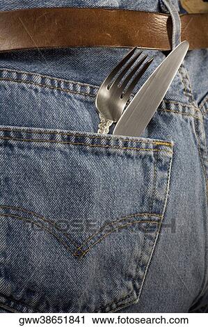 Stock Image - Close-up of a kitchen knife and a fork in the pocket of a pair of jeans. Fotosearch