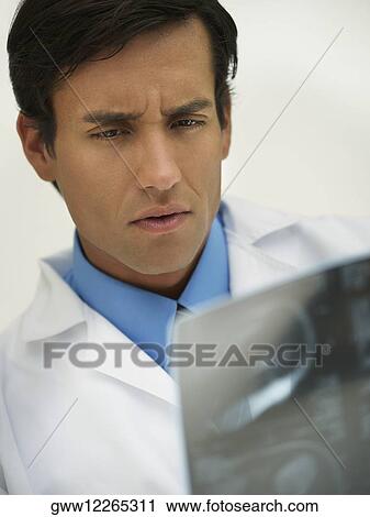 Stock Image - Close-up of a male doctor looking at an X-Ray report. Fotosearch